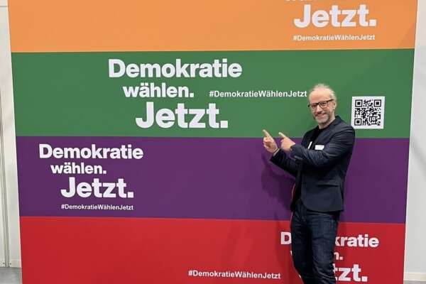 Markus zeigt auf das Plakat von Demokratie Jetzt 