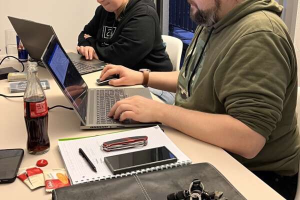 Eine Frau und ein Mann arbeiten an jeweils einem Laptop an einem Tisch. 