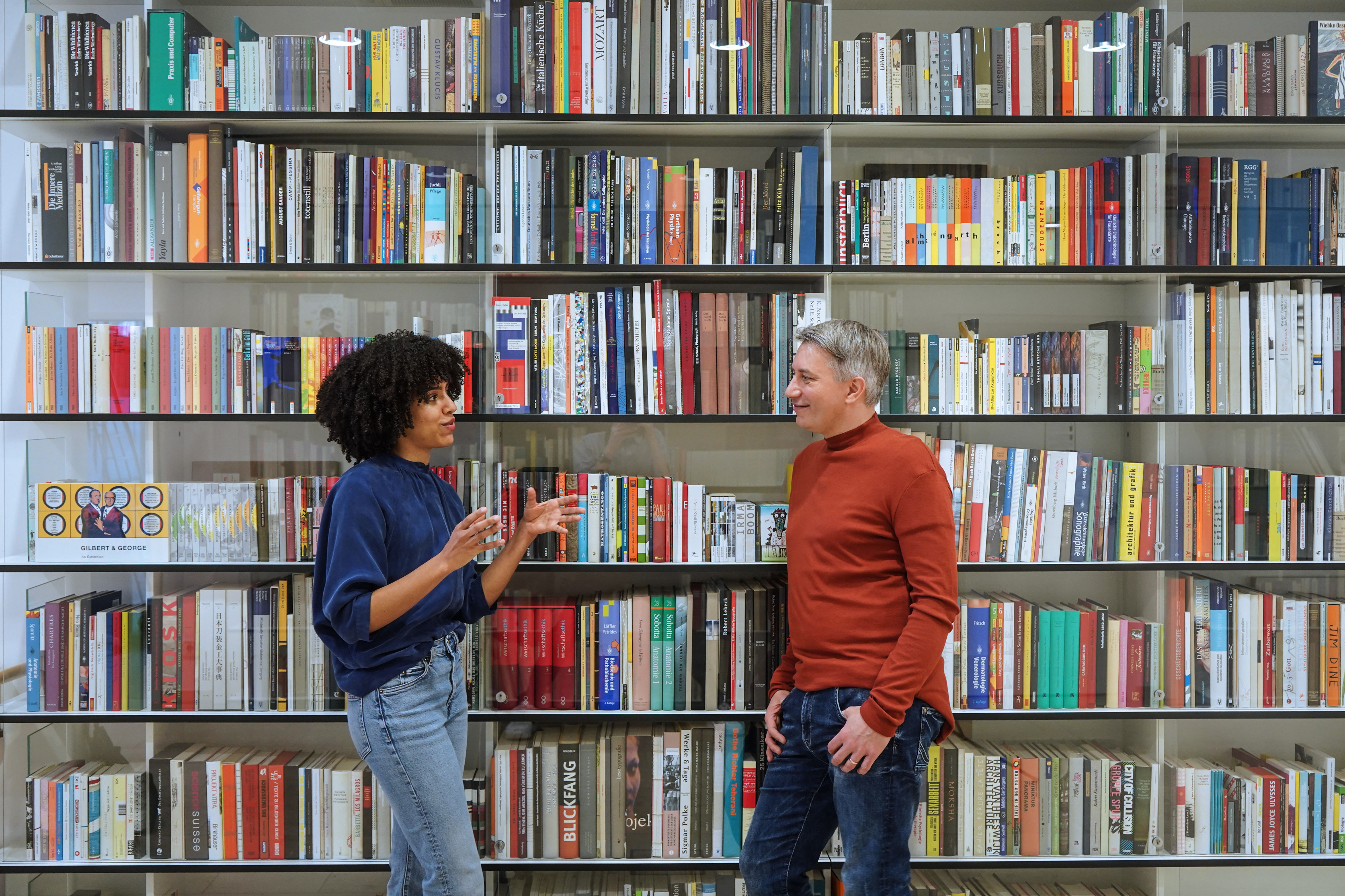 Zwei MVB-Mitarbeiter unterhalten sich vor einem großen Bücherregal.