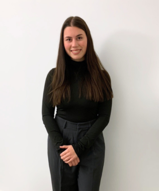 Yelda Altan steht vor einer weißen Wand und lächelt.