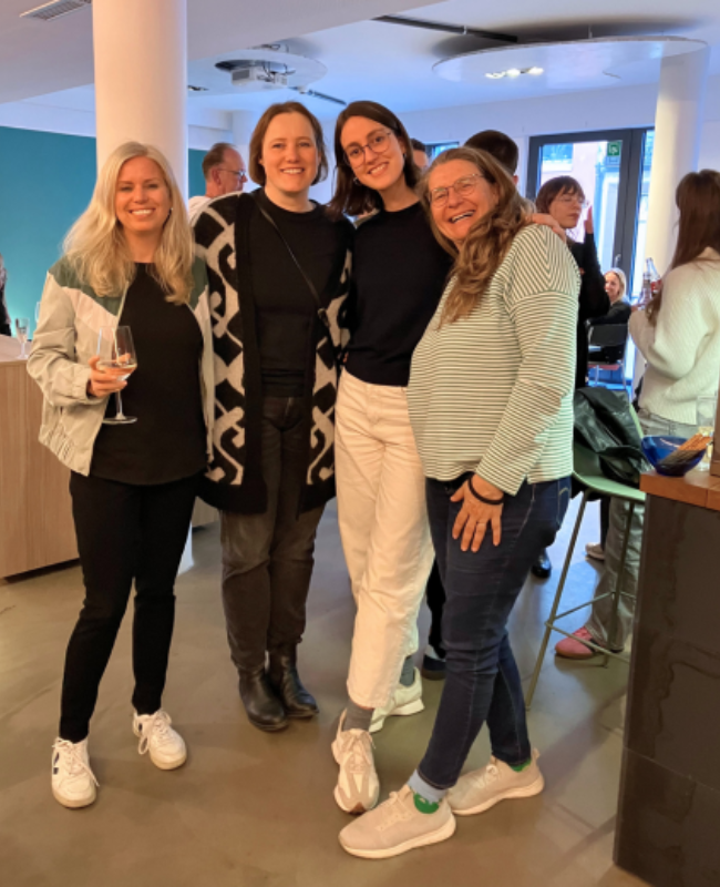 Vier Mitarbeiterinnen stehen bei einer Party zusammen.