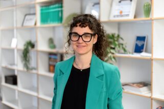 Susanne Breuer steht vor einem Bücherregal im Haus des Buches.