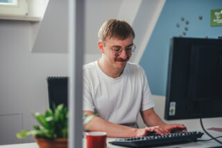Eine Person arbeitet an ihrem Arbeitsplatz vorm PC.