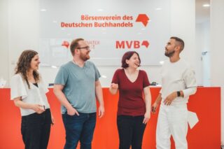 Vier Personen unterhalten sich lachend vorm Empfang des Haus des Buches.