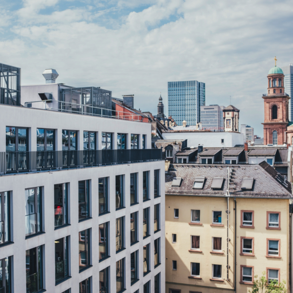 Blick auf einen Bauteil des Haus des Buches, im Hintergrund ist die Frankfurter Skyline sowie die Frankfurter Paulskirche zu sehen