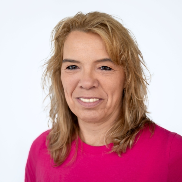 Portrait von Gabriele Hansch die in die Kamera lächelt und ein pinkes Oberteil trägt