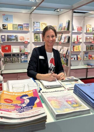Katharina Oppitz, die am Stand von Livro in die Kamera schaut und lächelt.