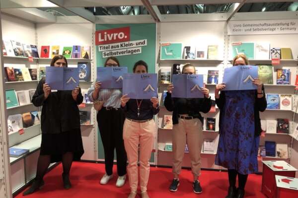 Fünf Frauen stehen am Livro stand und halten jeweils ein blaues Livro Magazin in den Händen.