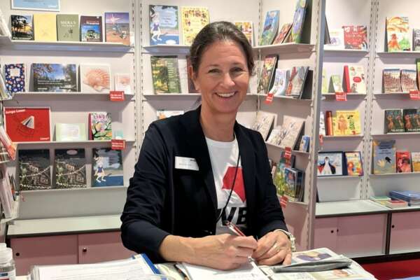 Katharina Oppitz, die am Stand von Livro in die Kamera schaut und lächelt.