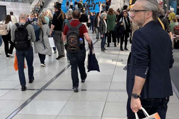 Menschen laufen in einer Messehalle 