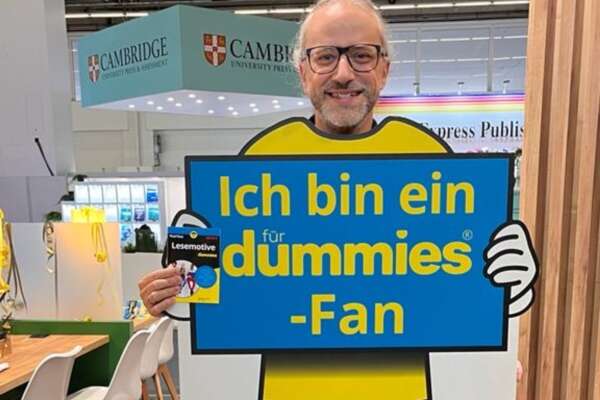 Markus hält ein Exemplar Lesemotive für Dummies in den Händen und ein Schild, auf dem steht "Ich bin ein dummies-Fan" 