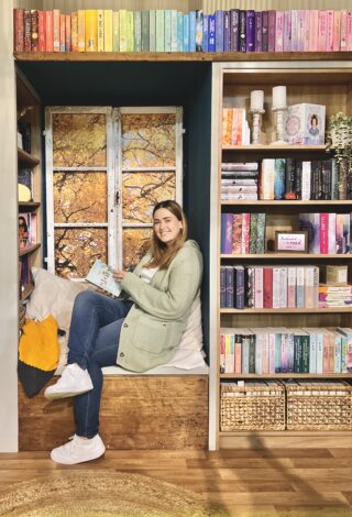 Bloggerin Livinginthousandworlds sitzt mit Buch in der Hand an einem herbstlichen Fenster