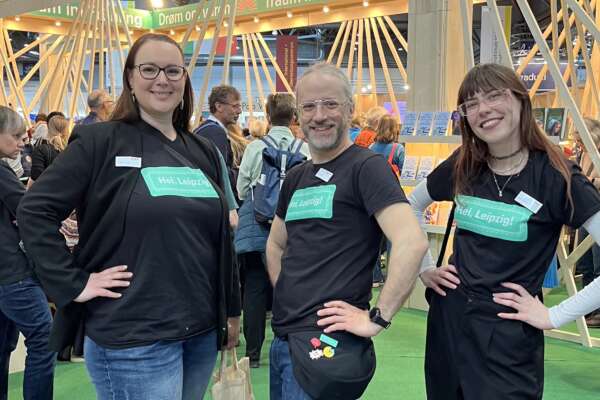 Katrin Friedl, Markus Fertig und Lorina Bischoff stehen vor dem Gastland-Stand