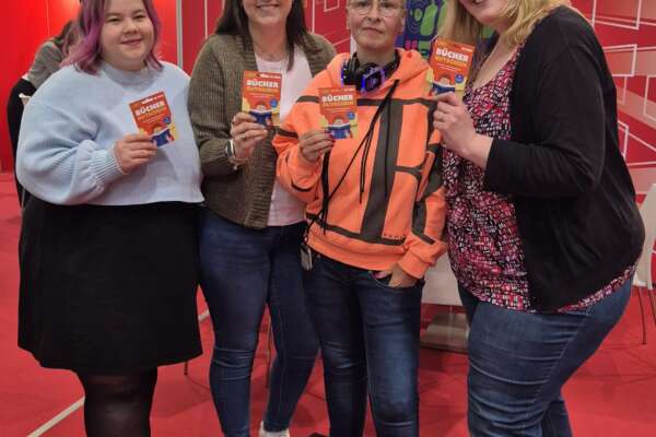 Vier Bloggerinnen halten einen Bücherscheck in der Hand.