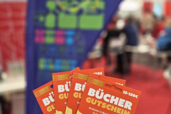 Vier Bücherschecks im Vordergrund, im Hintergrund eine Beachflag von Meet & Dance