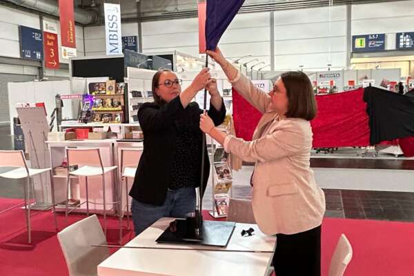 Zwei Frauen bauen eine Beachflag auf.