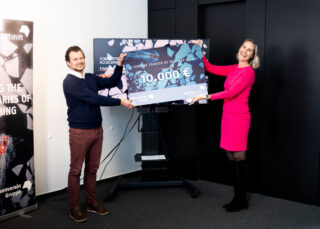 Gewinner und Gewinnerin halten ihren Sieger-Scheck